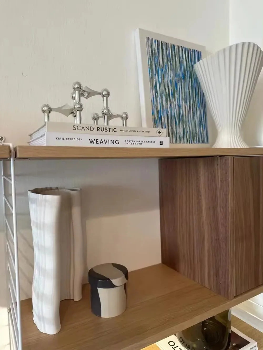 Molekyle nordisk lysestage i sølvfarvet metal – stylet på reol med designbøger og vase – Bo Studio